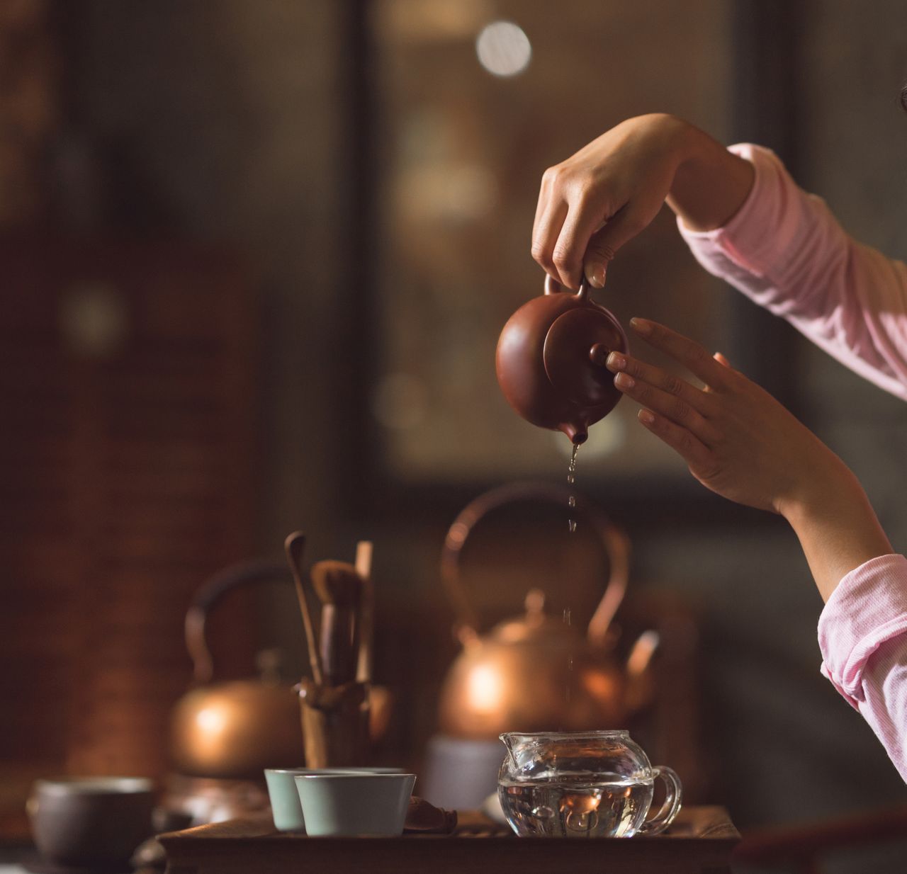 Người pha trà đang rót trà từ ấm gốm, hơi trà bốc lên